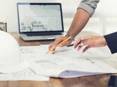 Architects discussing a project in the office Architect or engineer team discussing a project design using blueprints and a laptop computer at the office before visiting work site.