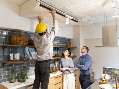 A repairman checking the air conditioner A repairman wearing a yellow helmet and checking the air conditioner